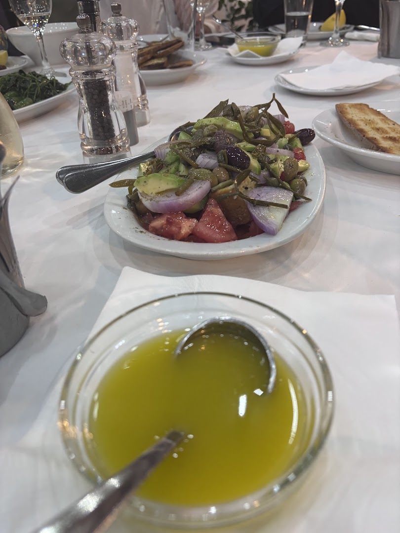 Εσωτερικός χώρος ελληνικής ψαροταβέρνας με στρωμένα τραπέζια και ζεστή ατμόσφαιρα.